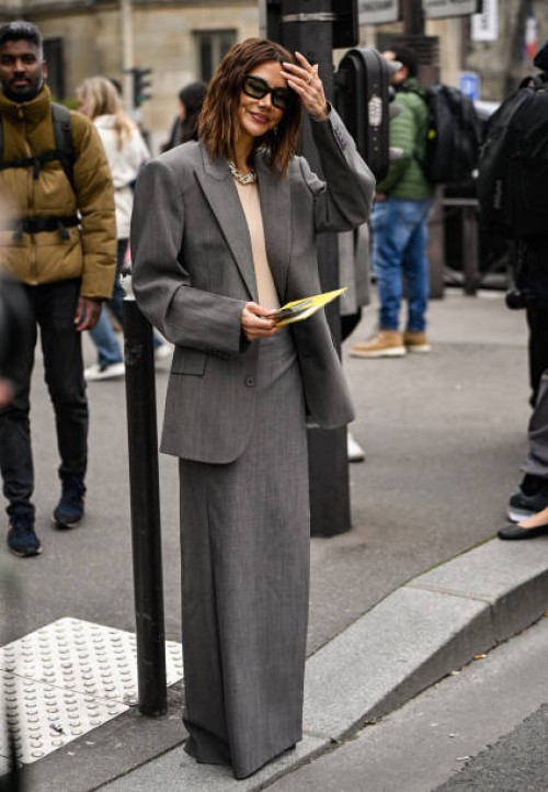Christine Centenera is seen wearing a gray suit and black sunglasses outside the Miu Miu show during the Womenswear Fall/Winter 2025/2026 as part of...