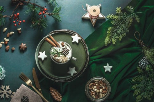 christmas background with hot chocolate with cream, biscuits, cutlery, nuts and fir green at green table - food stock pictures, royalty-free photos & images
