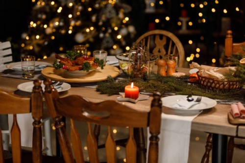 christmas lights glistening in the background behind a rustic dining table set for a christmas dinner party - home decoration stock pictures, royalty-free photos & images