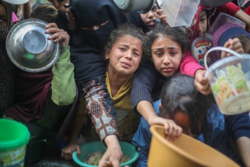 Citizens queue for food that is cooked in large pots and distributed for free during war-time on December 28, 2023 in Rafah, Gaza. More than 20,000...