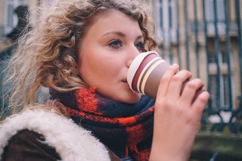 city student sipping a takeaway coffee on a winter day - junk food stock pictures, royalty-free photos & images