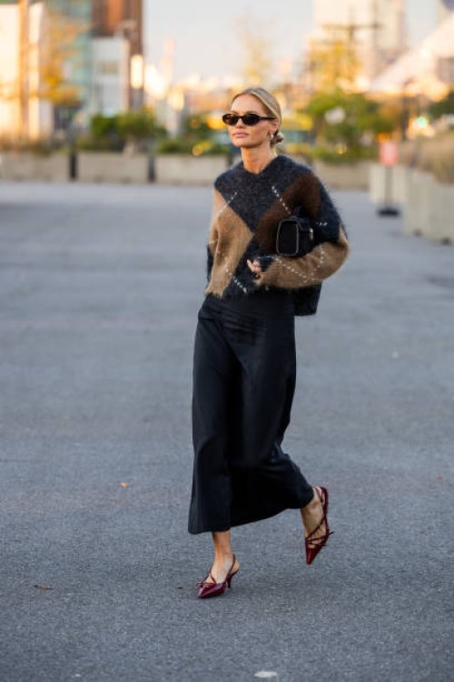 Claire Rose Cliteur wears brown black beige cashmere jumper, black wide leg pants, red heels, bag, sunglasses outside COS on September 12, 2023 in...