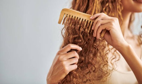 cleaning, beauty and hair care by woman brush and style her natural, curly hair in bathroom in her home. hygiene, frizz and damage control with female hands comb natural hair in morning routine - hairstyle stockfoto's en -bee