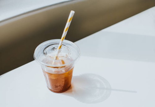 clear plastic cup half full of iced coffee, with a paper straw - junk food stock pictures, royalty-free photos & images