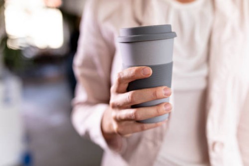 close-up of a businesswoman holding recycable takeaway coffee cup - junk food stock pictures, royalty-free photos & images