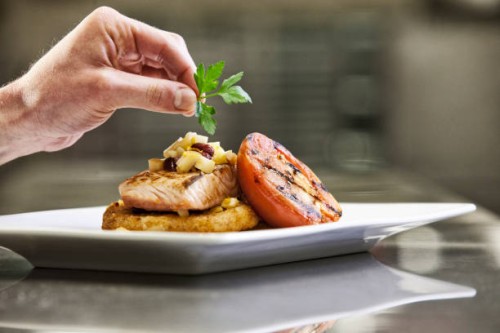 close-up of a chefs hands adding a garnish to a salmon dinner plate. - food stock pictures, royalty-free photos & images