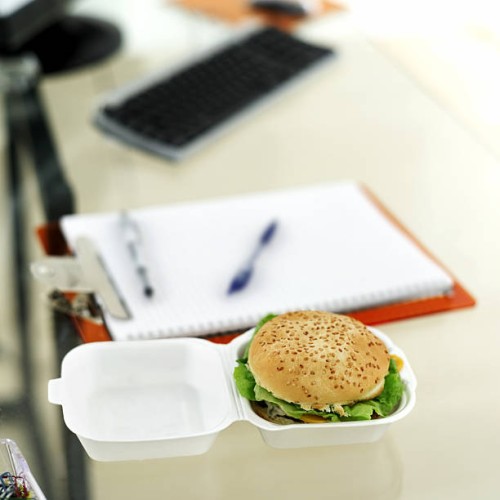 close-up of a hamburger in a box lying on a desk - junk food stockfoto's en -beelden