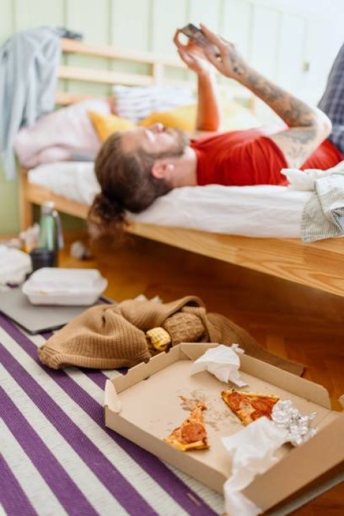 close-up of a man eating pizza in bed while looking at his smartphone - junk food stock pictures, royalty-free photos & images