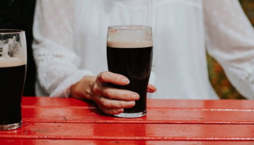 close-up of a woman holding a pint of stout - garden decoration photos et images de collection