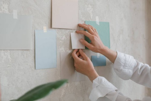 close-up of a woman taping colour paper samples to a wall - home decoration stock pictures, royalty-free photos & images