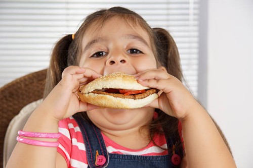 close-up of caucasian girl with pigtails eating a burger - junk food stock pictures, royalty-free photos & images