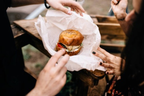 close-up of couple with a hamburger outdoors - junk food stock pictures, royalty-free photos & images