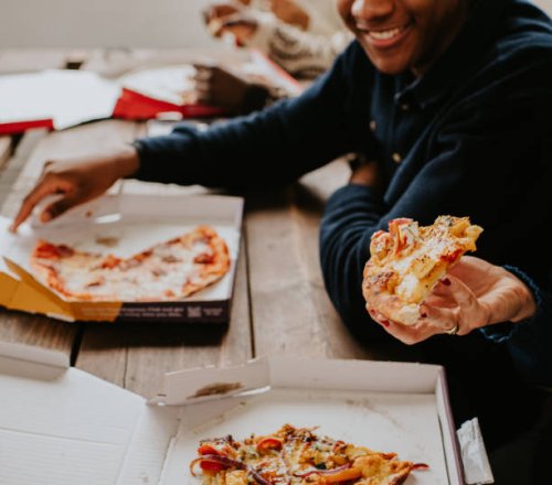 close-up of hands holding freshly delivered pizza - junk food stock-fotos und bilder
