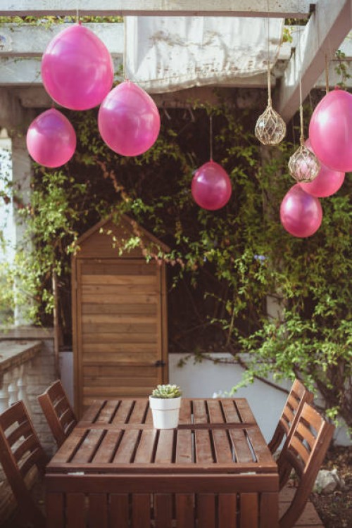 close-up of pink balloons and light decorations hanging over a garden table - garden decoration stock pictures, royalty-free photos & images