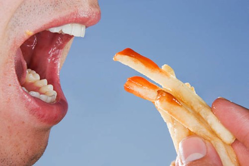 close-up of someone eating french fries - junk food stock pictures, royalty-free photos & images