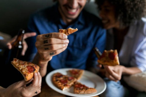 close-up of tattooed man with friends holding pizza slice - junk food stock pictures, royalty-free photos & images