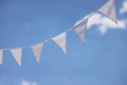 close-up of white flag garland against blue sky. garden party, summer festival, birthday party, baptism or wedding. - garden decoration stock pictures, royalty-free photos & images