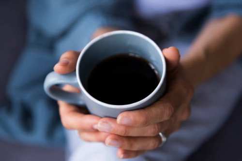 close-up of woman holding coffee cup at home - coffee stockfoto's en -beelden