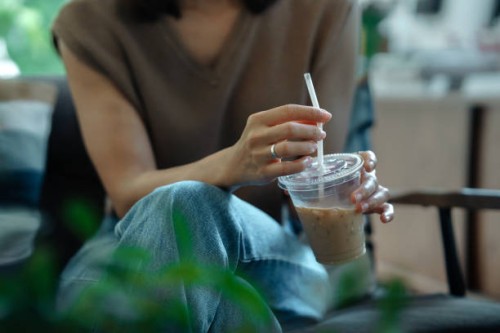 close-up of woman holding disposable cup of coffee. - junk food stock pictures, royalty-free photos & images