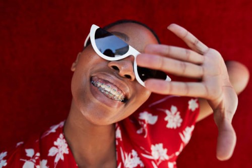 close-up of young woman gesturing against red wall - fashion stock pictures, royalty-free photos & images