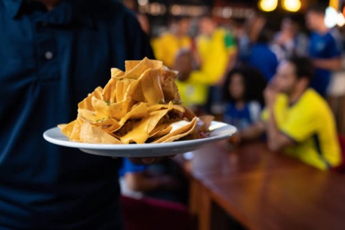 close-up on a waiter serving nachos at a sports bar - junk food stock pictures, royalty-free photos & images