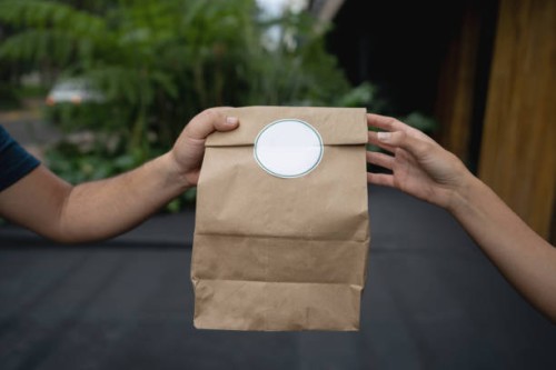 close-up on a woman delivering a food order to a customer - junk food stock pictures, royalty-free photos & images