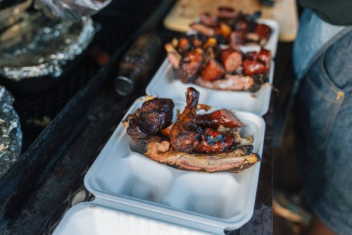 close-up shot of a compostabale takeout container with bbq chicken drumsticks and ribs from a food truck or traveling smoker catering company - junk food stock pictures, royalty-free photos & images