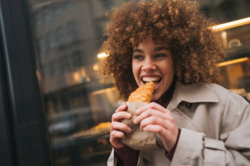 close up beautiful young woman eating croissant outdoors - junk food stock pictures, royalty-free photos & images