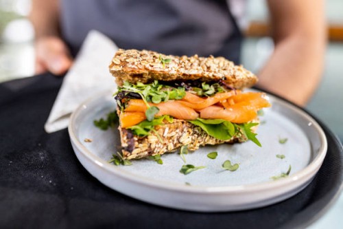 close up from fresh salmon sandwich serving from waiter - junk food stock pictures, royalty-free photos & images