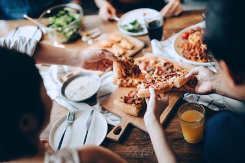close up of a young group of friends passing and serving food while enjoying together. they are having fun, chatting and feasting on food and drinks at dinner party - food stock pictures, royalty-free photos & images