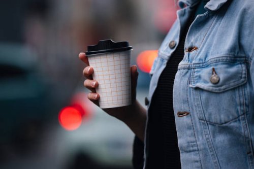 close up of an anonymous woman walking and holding a paper coffee cup - junk food stock pictures, royalty-free photos & images
