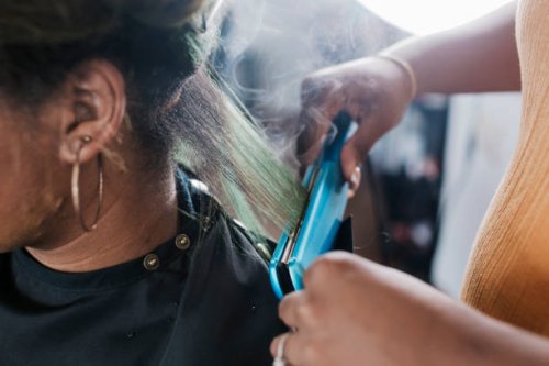 close up of black hairdresser straightening client's hair - hairstyle stock pictures, royalty-free photos & images