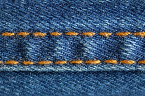 close up of golden stitches on blue denim jeans - fashion stock-fotos und bilder
