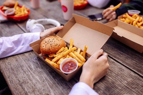 close up of hands holding box with burger at street food restaurant - junk food stock pictures, royalty-free photos & images