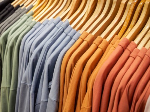 close up of stack of t-shirts on hangers and racks in department store in london, uk. plain standard style shirts in original stone wash and earthy colours and patterns - fashion stock pictures, royalty-free photos & images