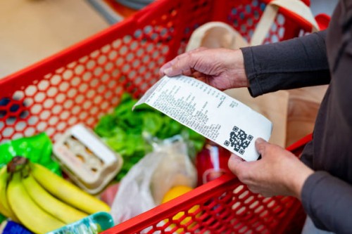 close up of unrecognizable customer checking her receipt after purchasing groceries in the supermarket - food stockfoto's en -beelden