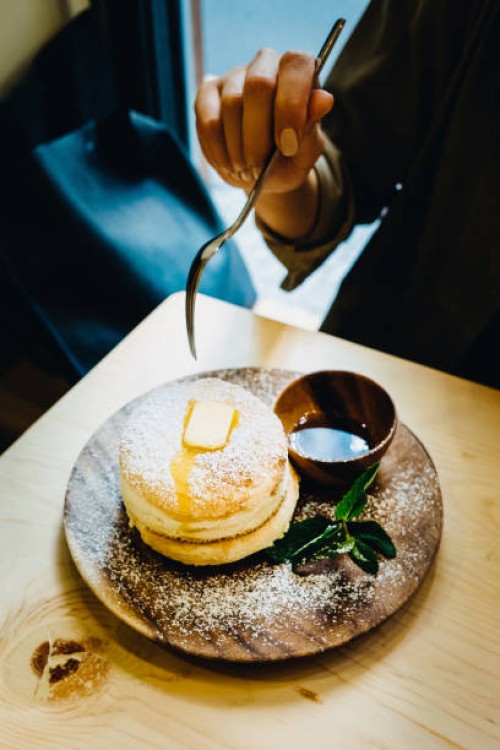 close up of woman eating fluffy pancake with butter and syrup on dinning table - junk food stockfoto's en -beelden