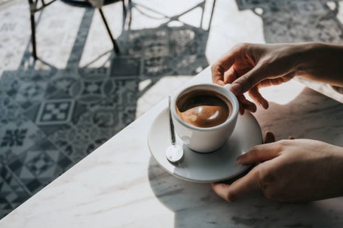 close up of woman's hand holding a cup of coffee, drinking coffee in outdoor cafe against beautiful sunlight, having a relaxing moment. enjoying life's simple pleasures - coffee stock pictures, royalty-free photos & images