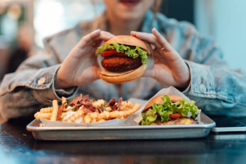 close up of young asian woman eating burger and fries in restaurant - junk food stock pictures, royalty-free photos & images