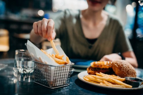 close up of young asian woman enjoying freshly served delicious burger with french fries in a restaurant. eating out lifestyle - junk food stock pictures, royalty-free photos & images