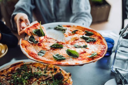 close up of young asian woman getting a slice of freshly made pizza. enjoying her meal in an outdoor restaurant. italian cuisine and culture. eating out lifestyle - junk food stock pictures, royalty-free photos & images