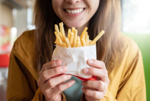 close up of young asian woman holding a french fries before eating. - junk food stock pictures, royalty-free photos & images