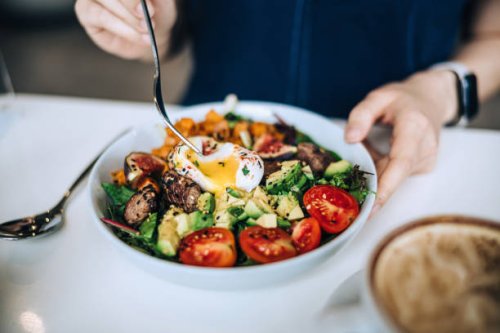 close up shot of a woman eating a dish of fresh beef cobb salad with a soft boiled egg and coffee at a cafe table. enjoying her healthy and nutritious lunch. maintaining a healthy and well-balanced diet. the concept of health
