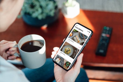 close up shot of woman ordering food delivery via food delivery app on her mobile phone - junk food stock pictures, royalty-free photos & images