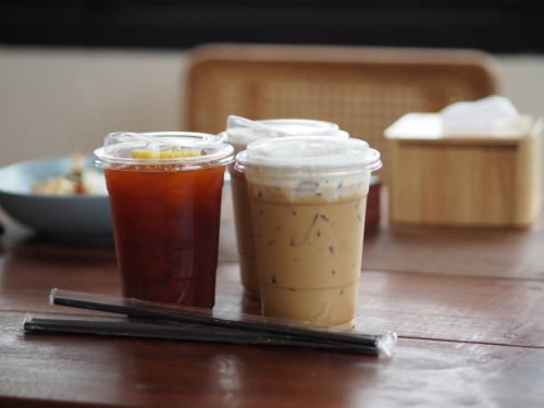 close up view of ice cubes in cold brewed coffee cappuccino in plastic cup put on bamboo wooden desk blurred background, drink beverage - junk food stock pictures, royalty-free photos & images