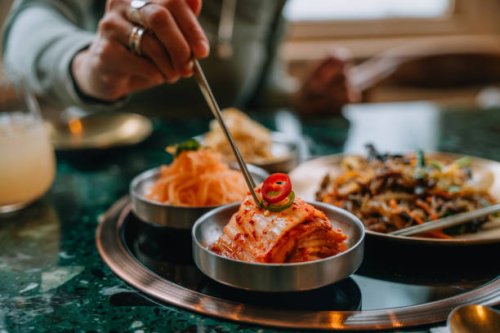 closeup of woman eating kimchi with chopsticks in korean restaurant - food stock pictures, royalty-free photos & images
