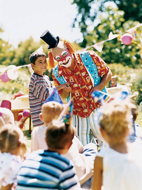 clown standing with boy and entertaining children at a birthday party - garden decoration stockfoto's en -beelden