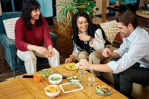 colleagues eating lunch together in a co-working office space - junk food stock pictures, royalty-free photos & images