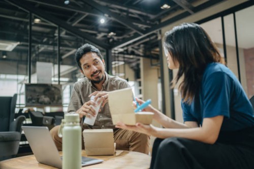 colleagues working while having lunch in the office - junk food stock pictures, royalty-free photos & images