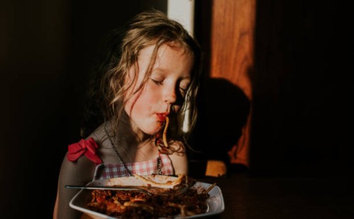 comical image of a sleepy little girl sucking spaghetti - food stock pictures, royalty-free photos & images